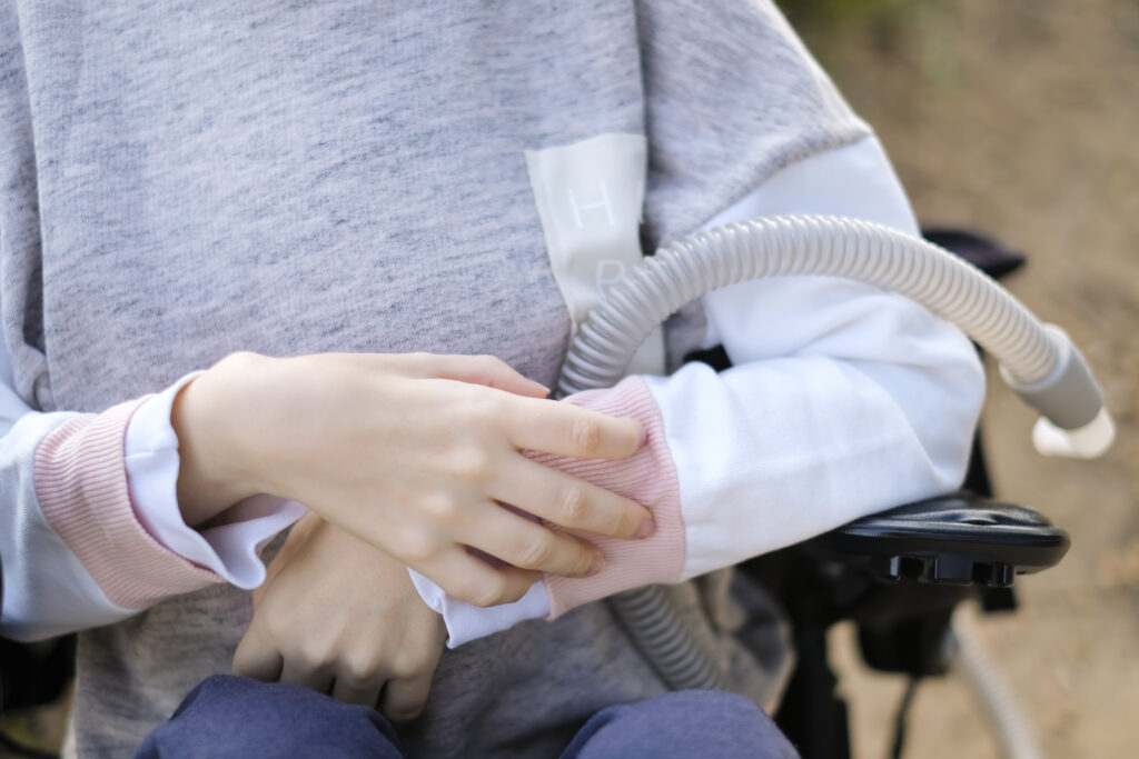 Hands of a person with muscular dystrophy holding a ventilator