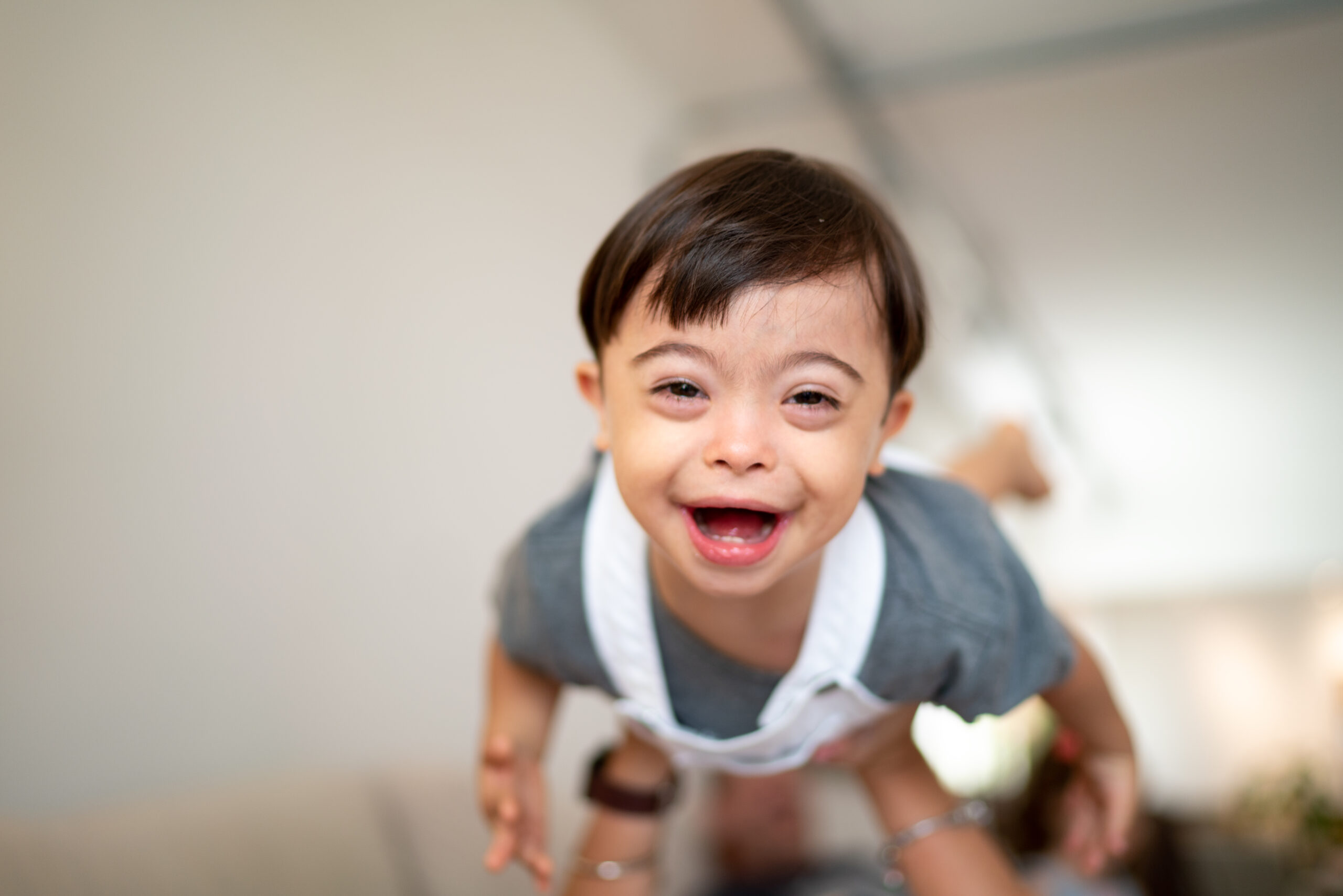 Photo of a boy with Down Syndrome laughing and being lifted up in the air