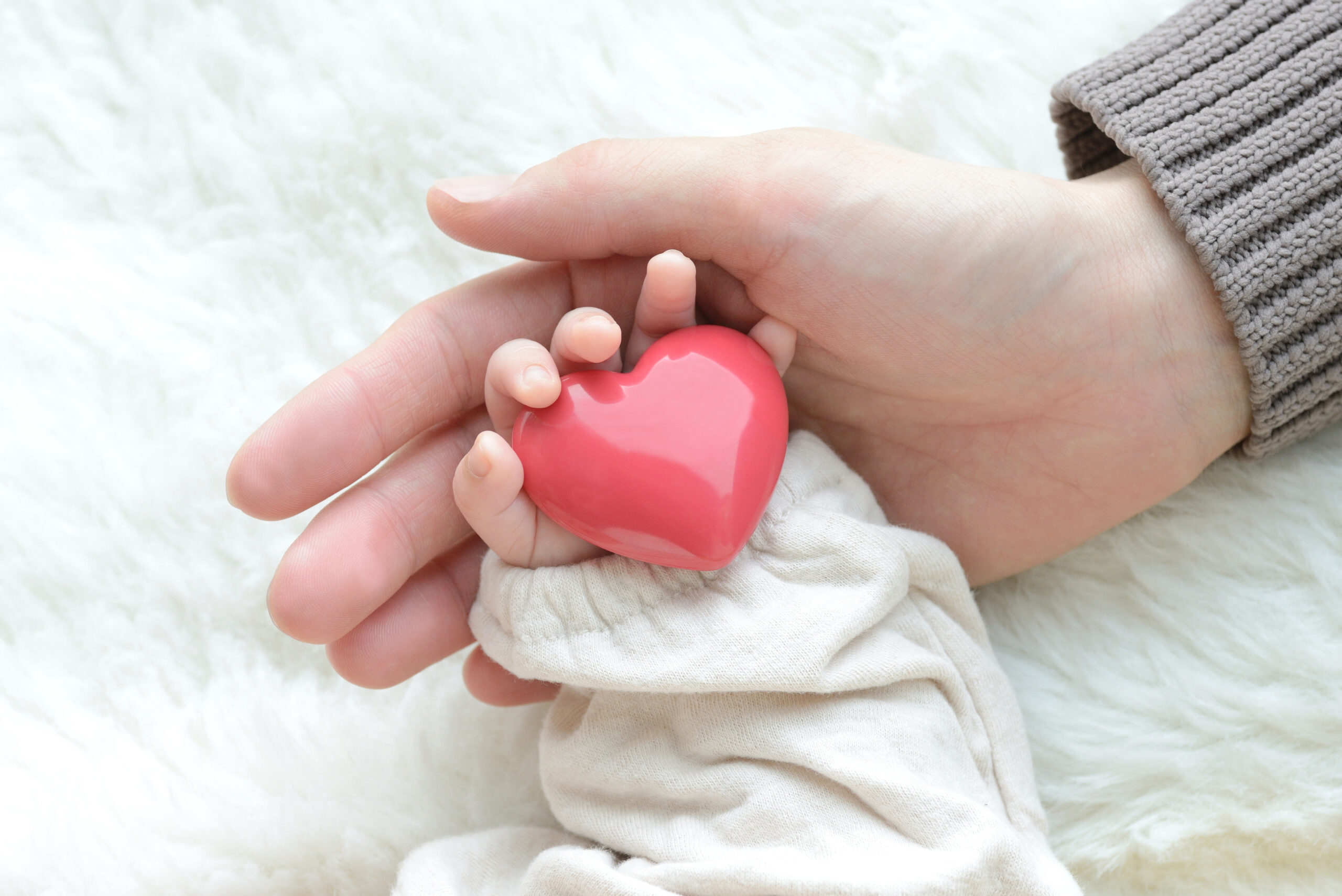 Hand of mother and baby holding a heart