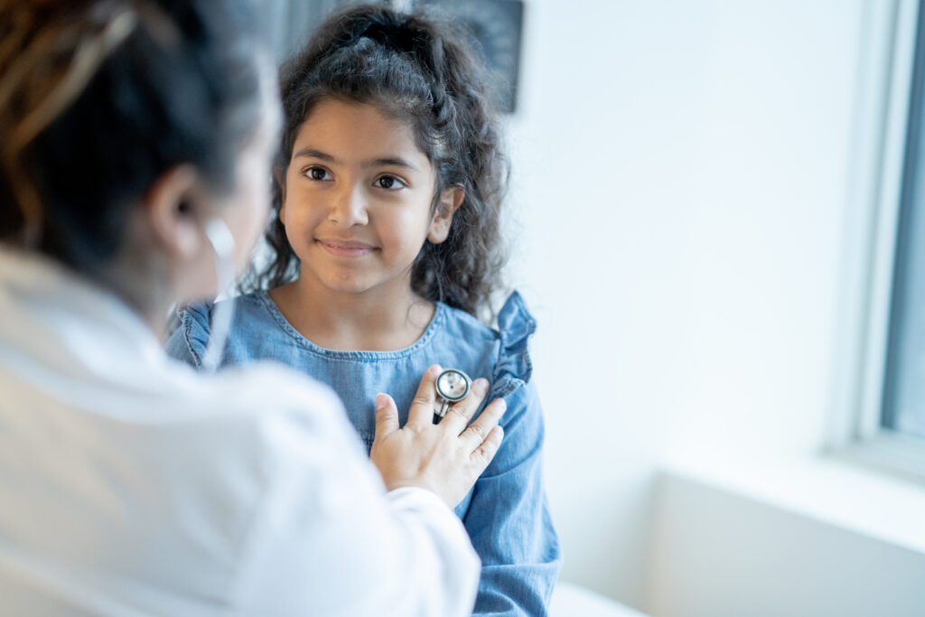 A doctor listening to a young girl's heart with a stethoscope